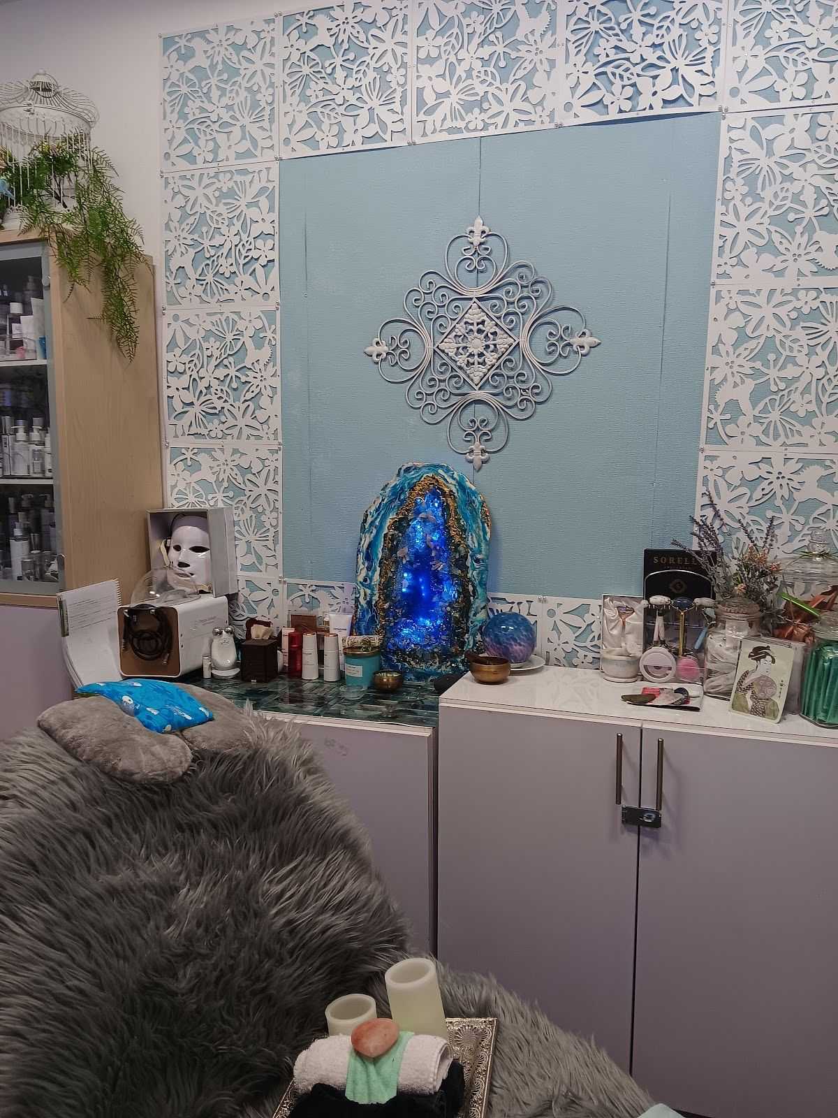 Alt text: Spa room with mystical decor, including a holographic face mask and glowing blue crystal.