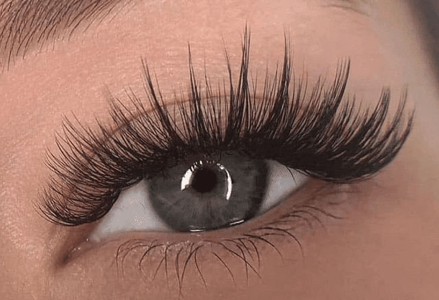 Close-up of a person's eye with long, thick false eyelashes.